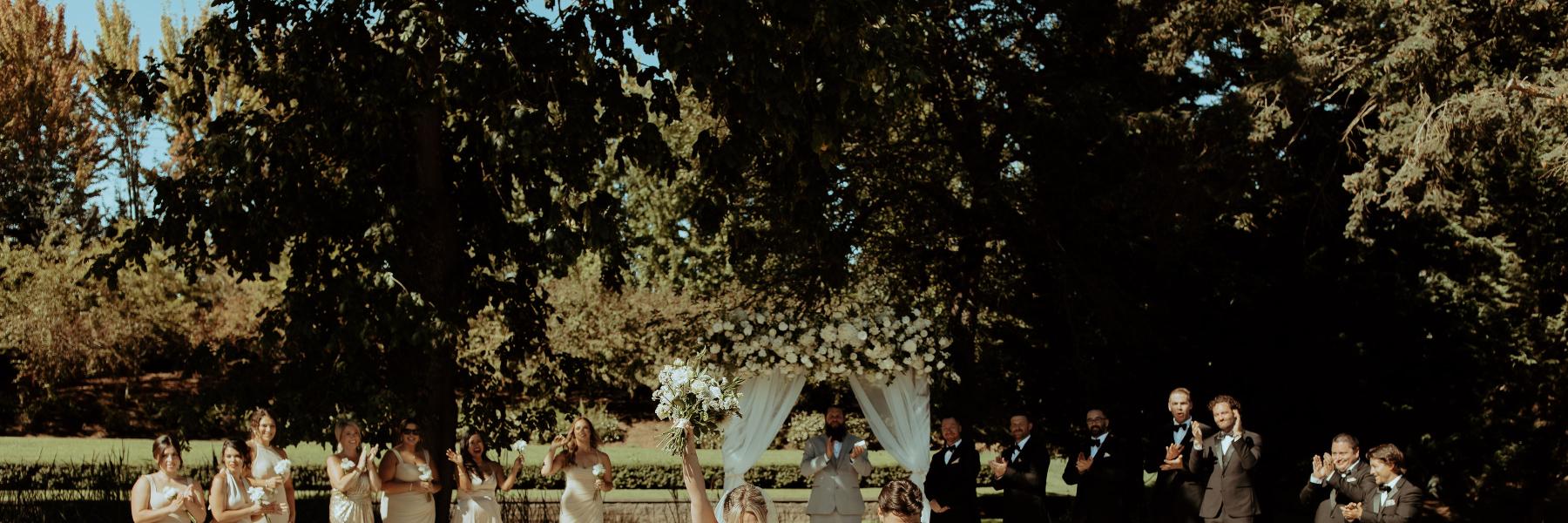 couple cheering and walking down aisle, ceremony arbor in background